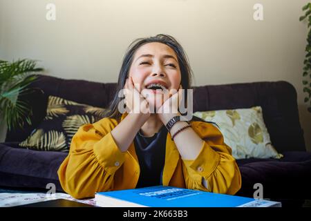 Woman in yellow jacket smiling. Work from home. Working at home. A woman working at home. Work from Anywhere. Happy working. Study at Home. Stock Photo