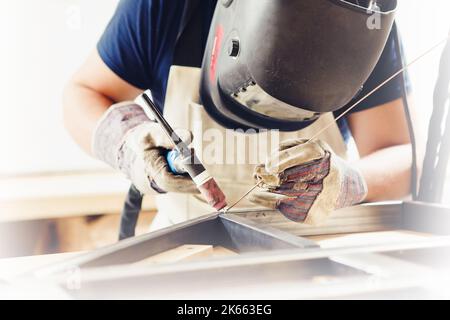 Male in face mask welds with argon-arc welding Stock Photo