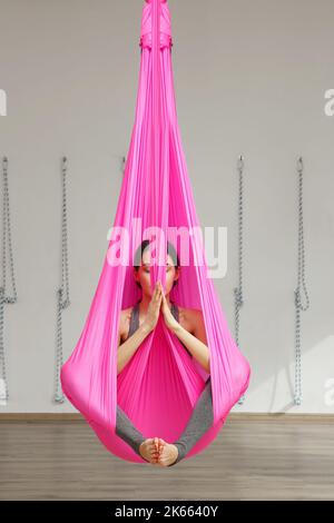 Girl lotus pose aerial yoga. Woman sits in hammock Stock Photo