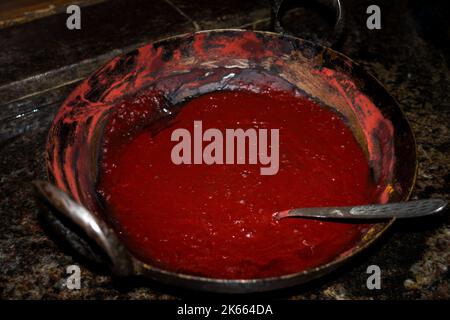 Henna Dye or Mehendi (Lawsonia inermis) made in a cast iron kadai . A reddish-brown dye made from the powdered leaves of a tropical shrub, used to col Stock Photo