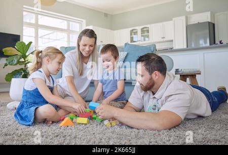 Happy family with two kids playing with colourful building blocks at home. Parents bonding with their two kids at home while playing educational game