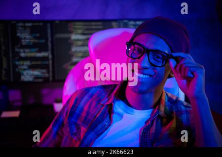 Photo of positive cheerful web designer sitting chair arm touch eyeglasses night shift workplace indoors Stock Photo