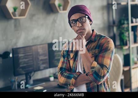 Photo of cool ponder programmer wear spectacles hat thinking debagging program indoors workplace workshop home Stock Photo