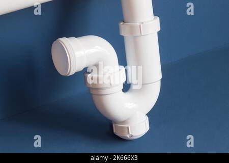 Detail of part of the siphon with a curved pipe with a drain cover on a blue studio background. Objects and maintenance. Stock Photo