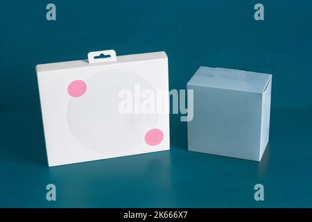 A white cardboard box with two decorative pink circles and a blank blue square box on a colorful blue studio background with copy space. Storage, deli Stock Photo