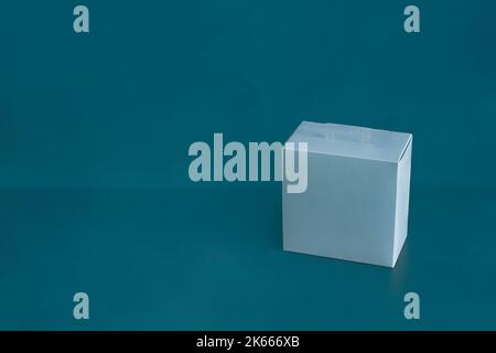 A blank blue square cardboard box on a colorful blue studio background with copy space. Gift, delivery, and shipping concept. Stock Photo