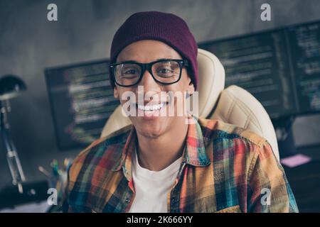 Photo of cheerful smiling guy dressed eyewear hat creating programming course indoors workstation workshop home Stock Photo
