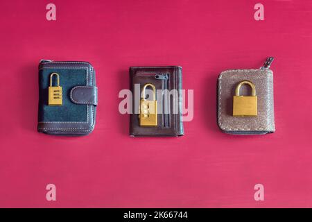 Three different wallets with different golden padlocks and locks on top on a colorful red studio background. Individual and collective investment. Stock Photo
