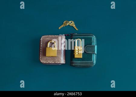 Two elegant and classic vintage wallets with a golden padlock on top of each one on a colorful textured background and two keys together. Finances and Stock Photo