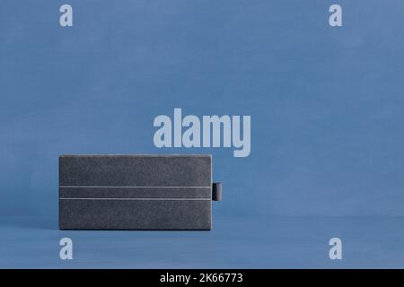 A stylish textured rectangular cardboard box with two thin white lines down the middle on a blue-painted studio background with copy space. Gift and p Stock Photo