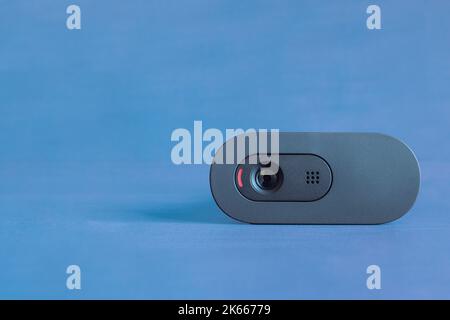 A webcam with the red light on ready to record on a colorful blue studio background with copy space. Security, technology, and entertainment. Stock Photo
