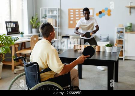 Back view at young woman with disability playing table tennis in office, inclusivity at workplace concept Stock Photo