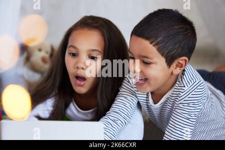 We have a whole world to explore right here. a little brother and sister using a digital tablet together at home. Stock Photo
