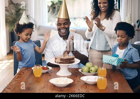 African american family celebrating birthday at home. Cheerful family with two parents and two little boys singing and clapping hands while standing Stock Photo