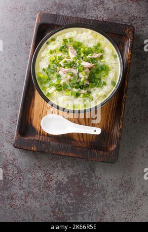 Homemade chicken soup with rice and green onions close-up in a bowl on the table. Vertical top view Stock Photo