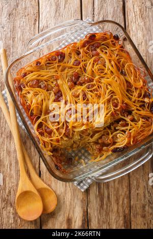 Kugel Yerushalmi also known as Jerusalem kugel is an Israeli sweet dish with noodles, raisins, cinnamon and sugar close-up in a glass form on the tabl Stock Photo