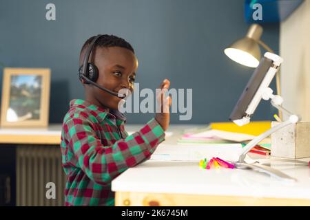 Smiling african american boy learning, using headphones and tablet at home Stock Photo