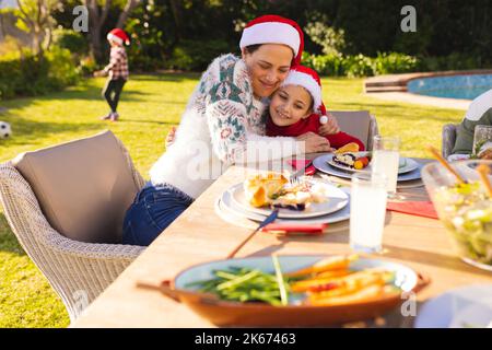 Caucasian mother and daughter spending time together and having christmas meal in the garden Stock Photo