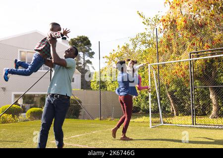 Happy african american family spending time together and playing football outside Stock Photo