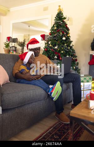 African american father and son siting on the sofa and using laptop Stock Photo