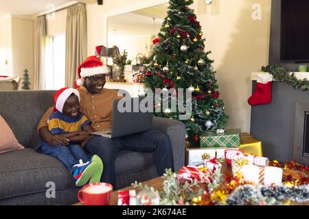 African american father and son siting on the sofa and using laptop Stock Photo