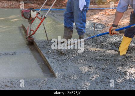 In construction new driveway, machine is used to align on compacted layer fresh concrete Stock Photo