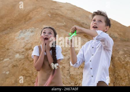 Children are delighted to watch a flying kite in the sky. Stock Photo