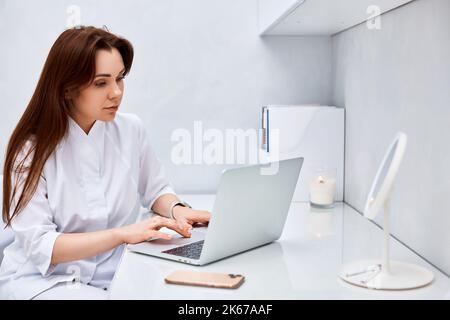female doctor in white medical uniform using laptop Stock Photo