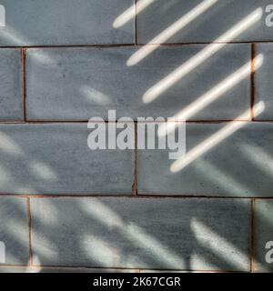A tile wall in a bathroom with shadows which can be used as a background. Stock Photo