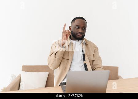 Portrait of a pensive black freelancer sitting at a table in his home office looking for an idea. Thoughtful black man found a solution to the problem Stock Photo
