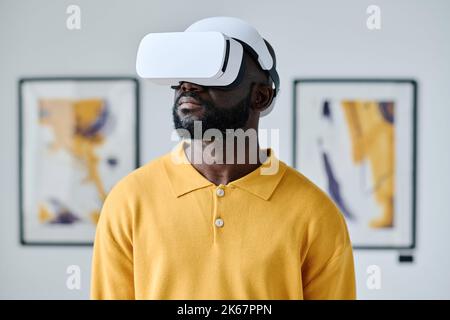African young man in virtual reality glasses visiting gallery of modern art Stock Photo