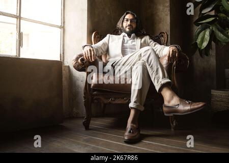 portrait of middle-eastern businessman manager wearing eyeglasses in a proud posture sitting comfortably on an armchair - business people lifestyle co Stock Photo