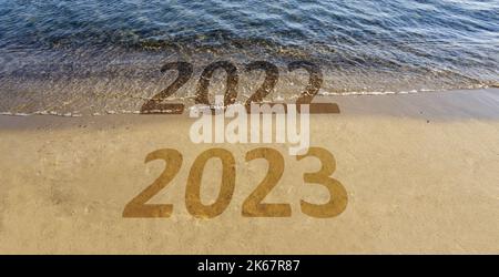 Happy New Year 2023 is coming. Transition from 2022 to 2023 text on beach sand. High resolution illustration image for banners, social media posts. Stock Photo