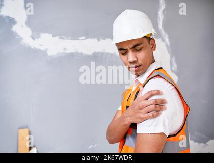 Construction worker holds shoulder in pain from workplace injury on site Stock Photo
