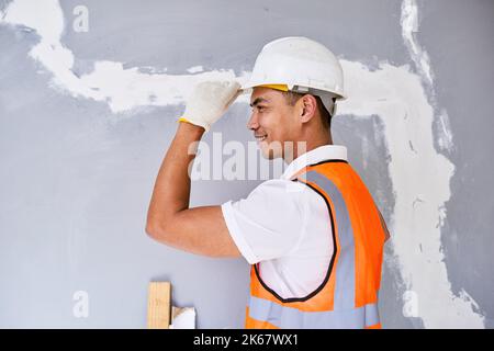 Portrait of an Asian construction worker tipping his hat facing left Stock Photo