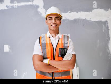 Portrait of a construction worker against cracked and repaired wall smiling Stock Photo