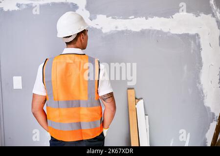 The back of a construction worker in uniform as he faces work in progress Stock Photo