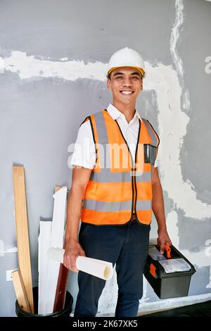 Portrait of a construction supervisor on site with building plans and toolbox Stock Photo
