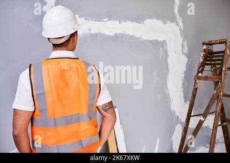The back of a construction worker in uniform as he faces work in progress Stock Photo