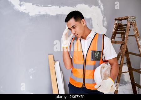 A construction worker scratches head in despair on home renovation project Stock Photo
