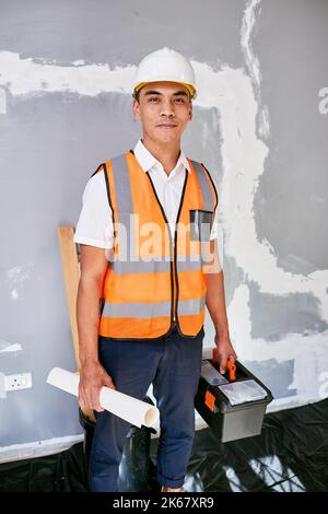 Portrait of a construction supervisor on site with building plans and toolbox Stock Photo
