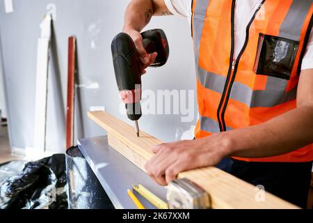 Close up of a construction worker's hands preparing to drill into wooden planks Stock Photo