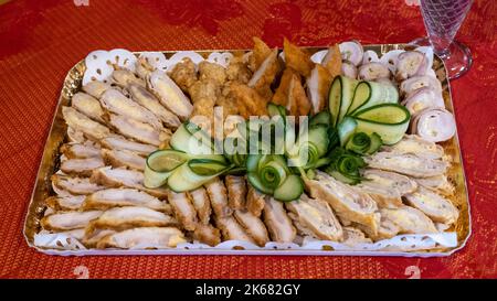 A plate of delicious seasoned chicken meat decorated with slices of fresh cucumber Stock Photo