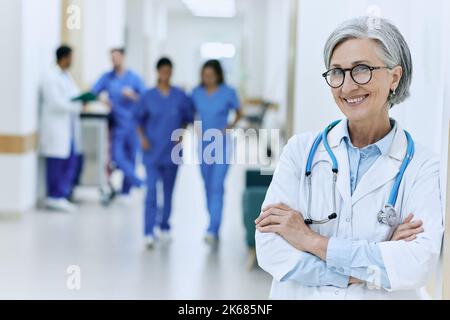 Mature female general practitioner with stethoscope standing in medical clinic or hospital, portrait. Health professional while working day Stock Photo