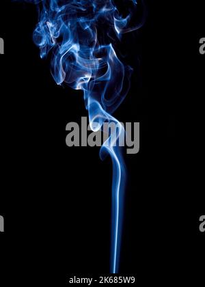 A thin stream of blue smoke curls and rises spectacularly over a black background Stock Photo