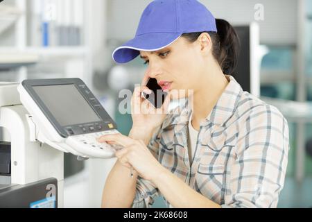 female repairer on the phone fixing printer Stock Photo