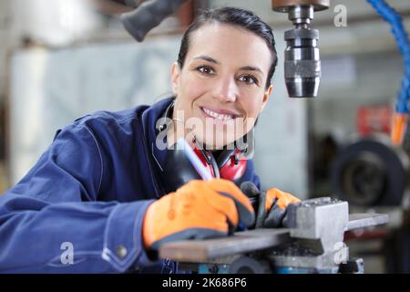 female apprentice using drill in factory Stock Photo