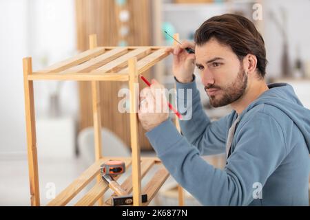 man installing wooden shelf at home Stock Photo