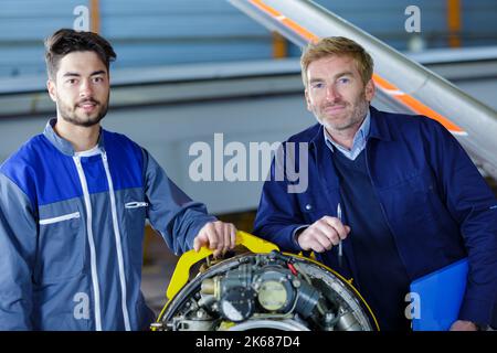 two flight engineers posing in a large aircraft hangar Stock Photo