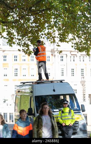 Two Just Stop Oil supporters climbed on top of a Metropolitan Police van outside Horse Guards Road in London on Wednesday (October 12) amid an ongoing Stock Photo